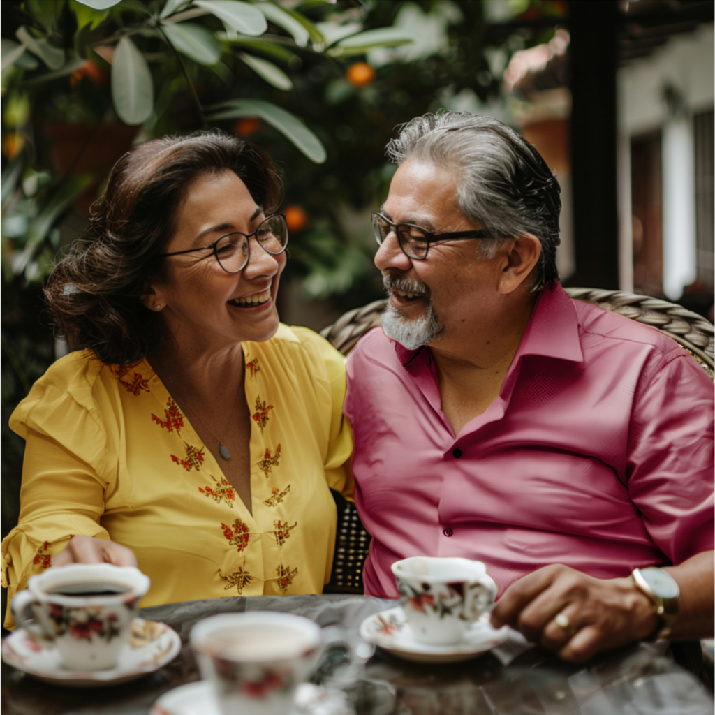 Older couple sitting at a table drinking coffee outside under fruit trees