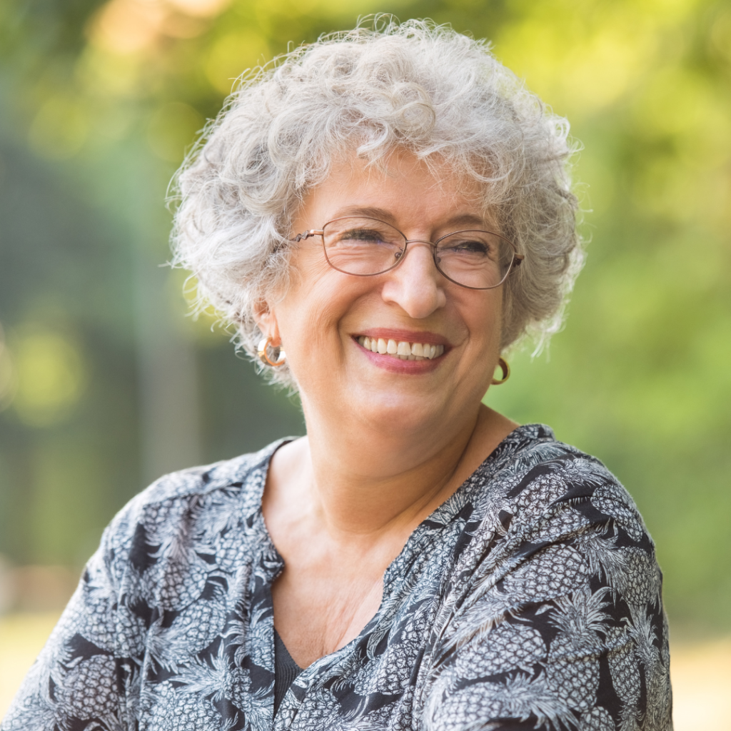 An older woman with glasses smiling and looking away